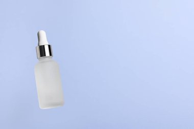 White translucent bottle with dropper with a beauty serum on a blue background. Glass packaging for cosmetic product, essential aroma oil. Skin care, hydration and nutrition with collagen. Levitation.