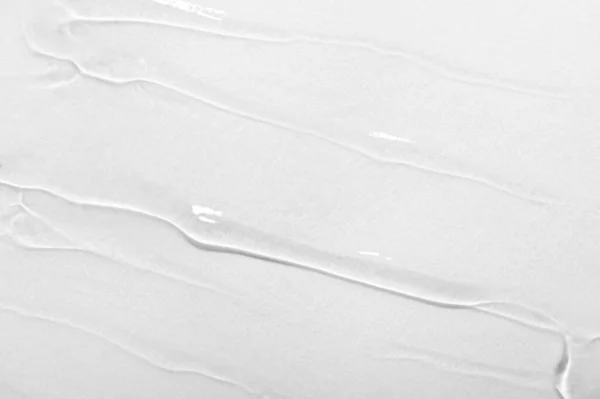 Transparent gel cream, serum, essential oil with bubbles on white background. Texture of beauty cosmetic product close-up. Moisturizing nourishing hyaluronic acid, cleansing skincare lotion.