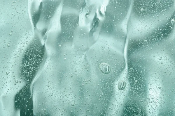 The transparent texture of the face skin care gel. Green natural liquid serum close-up. Cosmetic beauty product with acids and hyaluronic acid. Natural hydration with aloe vera.