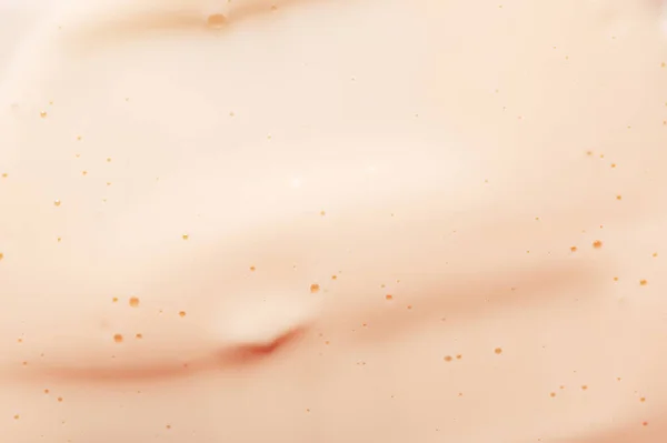 Crema facciale di fondazione beige chiaro con piccole bolle prodotti di trucco contemporanei come sfondo estremo da vicino vista superiore. — Foto Stock