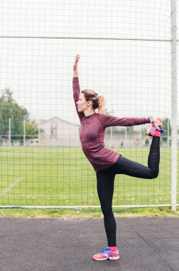 Eşofmanlı kadın stadyumda zor bir egzersiz yapıyor.