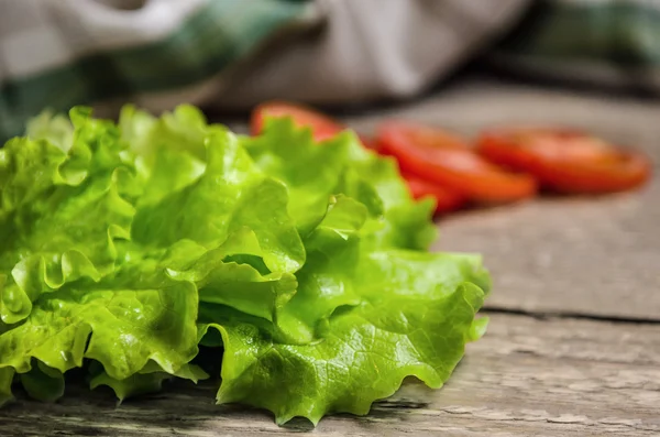 Ensalada verde fresca y tomates en la mesa — Foto de Stock