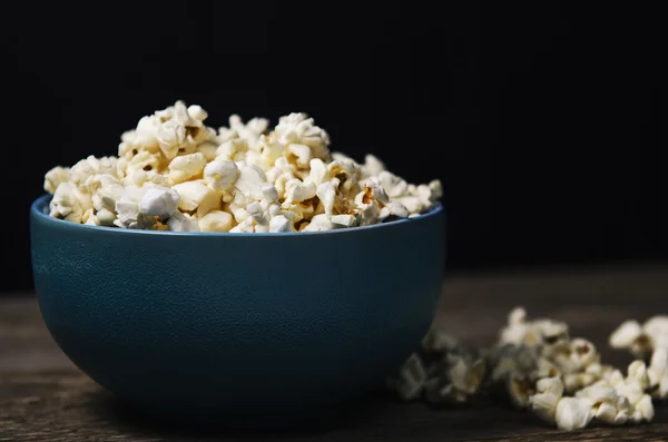 Popcorn i en skål på träbord — Stockfoto