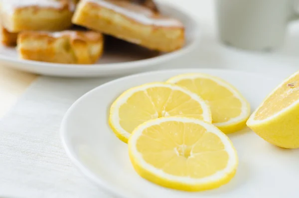 Fette di limone un piatto bianco sul tavolo — Foto Stock