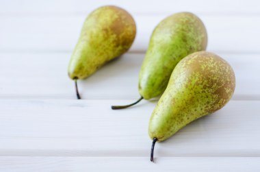 ahşap beyaz masa üzerinde üç yeşil armut