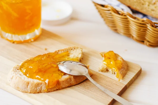 Šíření lžíce pomerančové marmelády na domácí čerstvý chléb — Stock fotografie