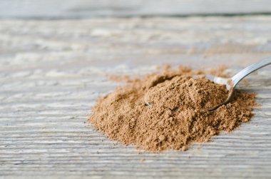 kaşık ve ahşap masa üzerine tarçın serpilir