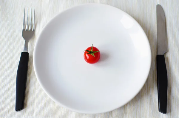 Tomate auf Teller mit Gabel und Messer serviert — Stockfoto