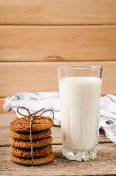 Biscoitos de aveia rústica em mesa de madeira com um copo de leite — Fotografia de Stock