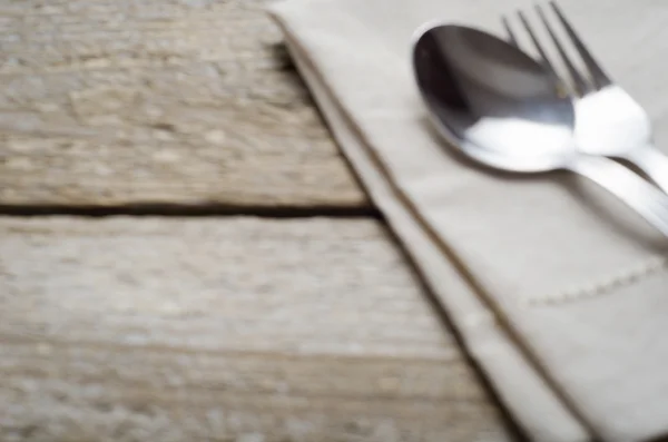 Blurred background with a napkin and cutlery on wooden table — Stock Photo, Image