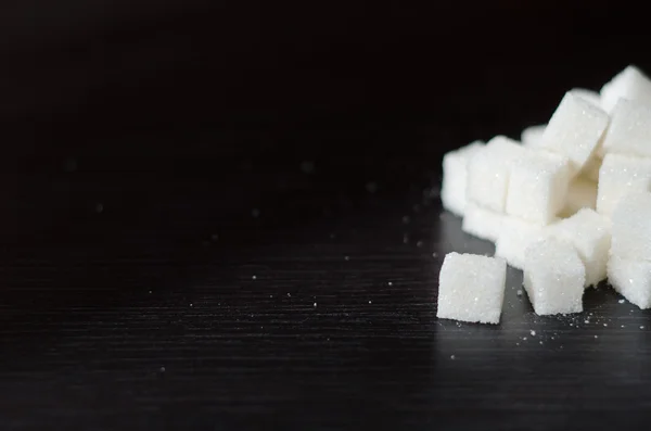 Cubes de sucre blanc empilés en tas sur le bureau noir — Photo