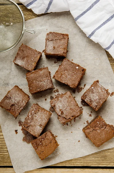 Brownie au chocolat en dés de papier cuisson sur une table en bois avec une serviette — Photo