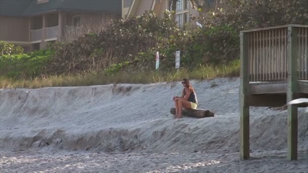 Dziewczyna siedzi wating zachód słońca na plaży — Wideo stockowe