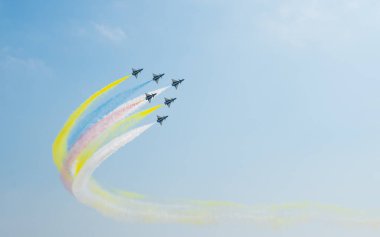 Mavi gökyüzünde, renkli dumanla uçan bir jet uçağı. Çin 'in Guangdong Eyaleti, Zhuhai' deki hava gösterisinde uzay sergisi..