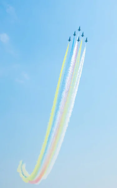Mavi gökyüzünde, renkli dumanla uçan bir jet uçağı. Çin 'in Guangdong Eyaleti, Zhuhai' deki hava gösterisinde uzay sergisi..