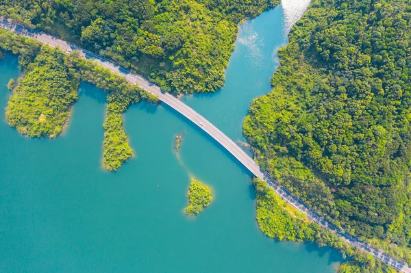 İHA 'dan Kırsal Yol' un üst görüntüsü, yeşil orman ve gölden geçiyor. Güneşli bir gün