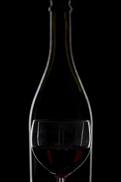 Garrafa de vinho e um copo de vinho sobre um fundo preto, minima — Fotografia de Stock