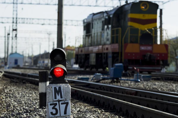 Semáforo ferroviário contra os trilhos de fundo e locomotiva — Fotografia de Stock