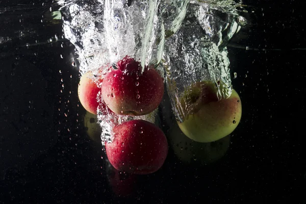 Manzanas en agua sobre fondo negro — Foto de Stock
