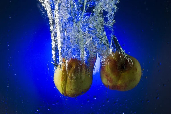 Nectarinas en el agua sobre un fondo azul — Foto de Stock