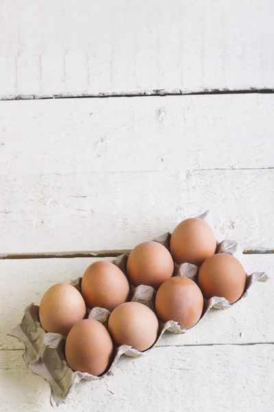 Œufs dans un plateau en carton contre des planches blanches . — Photo