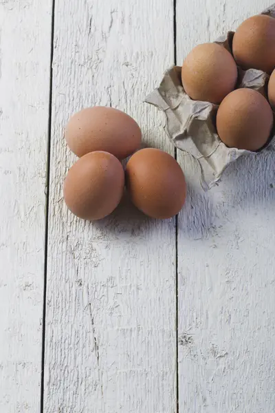 Œufs dans un plateau en carton contre des planches blanches . — Photo