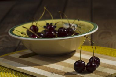 Ahşap arka plan üzerinde bir kase çilek kiraz.