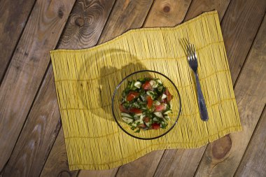 Ahşap zemin üzerine sarı bambu hasır salataya.