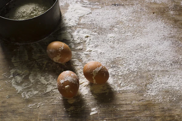 Ovos e farinha em uma peneira com um fundo de madeira . — Fotografia de Stock