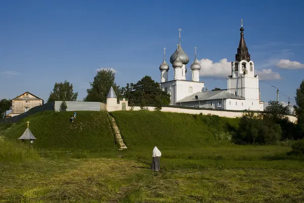 Летний пейзаж со старым монастырем и пешеходной монашкой — стоковое фото