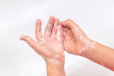 Çocuk ellerini sabunla köpükler, beyaz arka planda yakın plan çekimler yapar. Hijyen konsepti. Hastalıkların önlenmesi, sağlık hizmetleri.