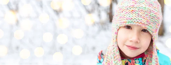 Close-up portrait of a beautiful Caucasian girl 6-7 years in a winter knitted hat with earflaps. — Stock Photo, Image