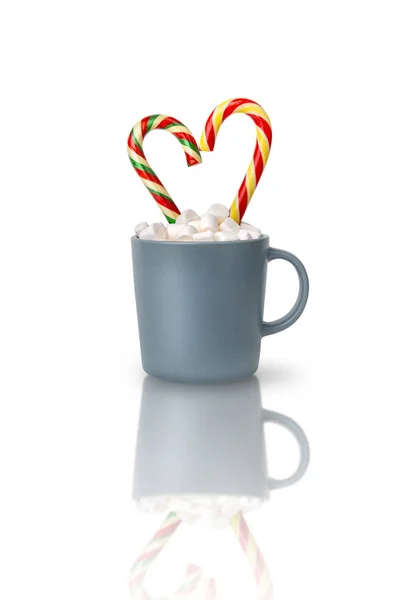 Kakao mit Marshmallows und zwei herzförmigen Zuckerstangen in einer grauen Tasse isoliert auf weißem Hintergrund mit Reflexion. — Stockfoto