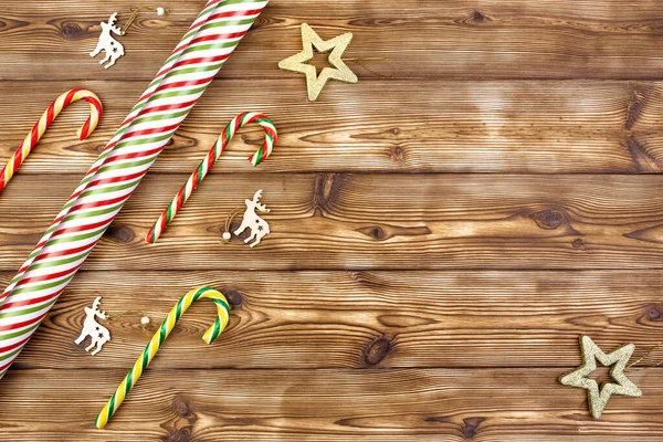 Decoraciones navideñas, papel de regalo a rayas y bastones de caramelo sobre un fondo de madera. Colocación plana, espacio de copia. — Foto de Stock