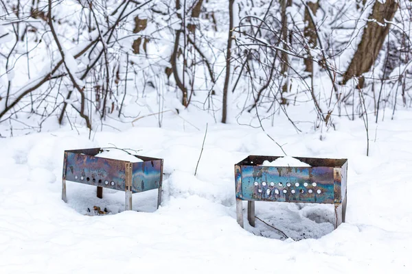 Dos barbacoa o brasero, olvidado en el bosque de invierno en la nieve. — Foto de Stock