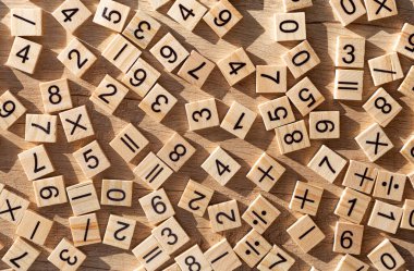 Sayılar ve işaretlerle saçılmış ahşap plaklar. Düz yatıyordu. Matematikte ders materyali.