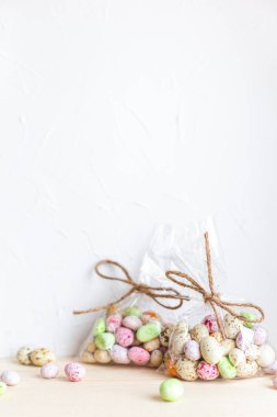 Çikolatalı Paskalya yumurtaları, şeffaf bir çantada jöleli şekerler, açık bir arka plan.