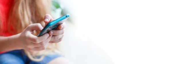 Mobile phone in the hands of a young girl close-up on a white background.