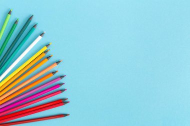 Mavi arkaplanda çok renkli kalemler, boşluğu kopyala.