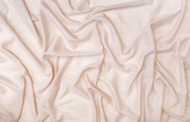Yumuşak katlarla örtülmüş güzel bej bir kumaştan soyut bir arkaplan.