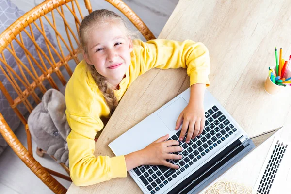 Chica caucásica 10-11 años, manos en el teclado del ordenador portátil, ojos entrecerrados, vista superior. — Foto de Stock