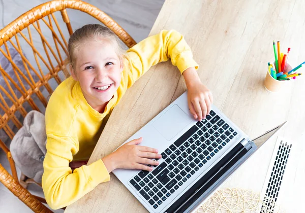 Caucásico chica se sienta en un escritorio, manos en el teclado del ordenador portátil, sonrisas, vista superior. — Foto de Stock
