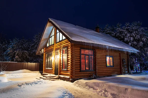 Casa de troncos rústica, pinos cubiertos de nieve, ventisqueros, fabulosa noche de invierno. — Foto de Stock