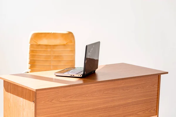 旁边是一张木制桌子 上面有一台笔记本电脑 旁边有一把皮椅 整个空间充满了晨曦和灿烂的阳光 — 图库照片