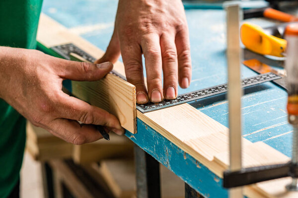 Carpenter's hands. Men's hands that hold a pencil and ruler for marking parts before production