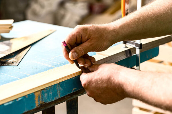 Carpenter's hands. Men's hands that hold a pencil and ruler for marking parts before production