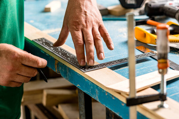 Carpenter's hands. Men's hands that hold a pencil and ruler for marking parts before production