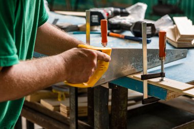 Marangoz atölyede el işçiliği için testere ve cetvel aletleri kullanarak inşaat malzemeleri veya ahşap mobilyalar üretiyor.