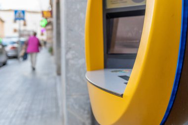 Campos, Balear Adaları / İspanya; Kasım 2020: İspanyol özel bankasının ATM 'sinin detayları. Arka planda, odaklanmamış insanların olduğu cadde.