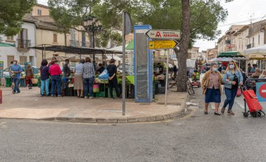 Campos, Balear Adaları / İspanya; Kasım 2020: Campos 'taki geleneksel sokak pazarında meyve ve sebze tezgahı. Covid-19 'un yeni sosyal önlemleri için yüz maskeli satıcı ve alıcılar